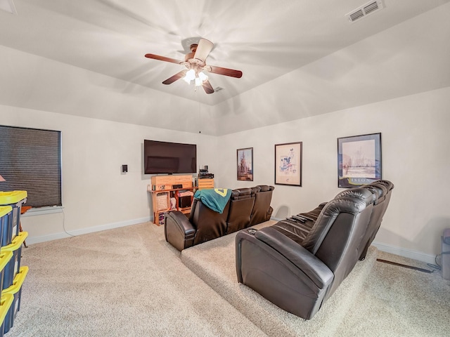 carpeted home theater room featuring a ceiling fan, a tray ceiling, visible vents, and baseboards