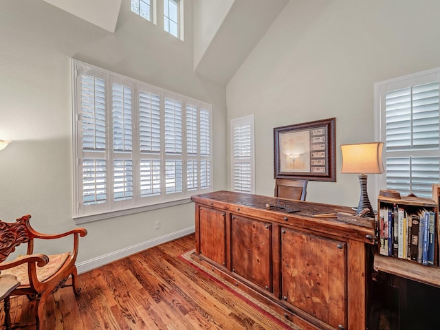 office area featuring a high ceiling, baseboards, and wood finished floors