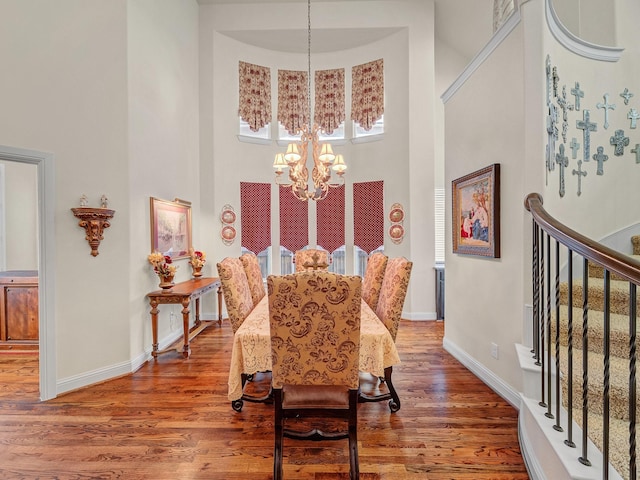 dining room with a chandelier, stairway, a high ceiling, and wood finished floors