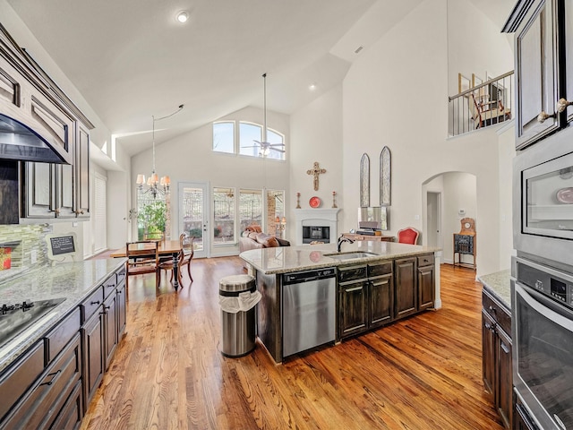 kitchen with stainless steel appliances, a sink, light wood-style floors, open floor plan, and a glass covered fireplace