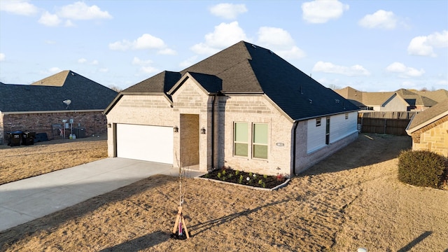 view of front facade with a garage, brick siding, fence, concrete driveway, and roof with shingles