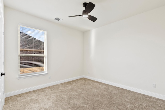 spare room with carpet floors, a wealth of natural light, visible vents, and a ceiling fan