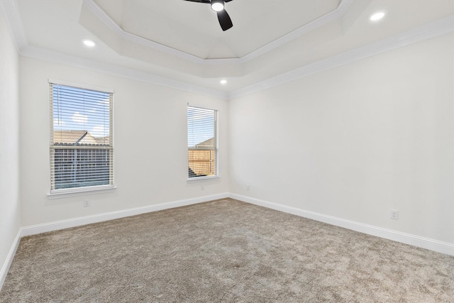 carpeted empty room with baseboards, ceiling fan, a tray ceiling, and crown molding