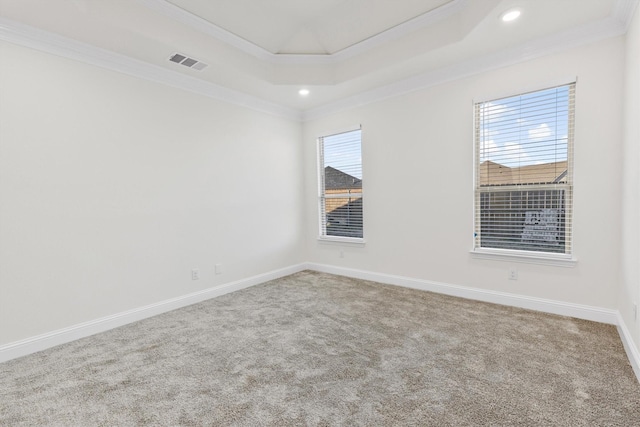 carpeted empty room with baseboards, a raised ceiling, visible vents, and crown molding