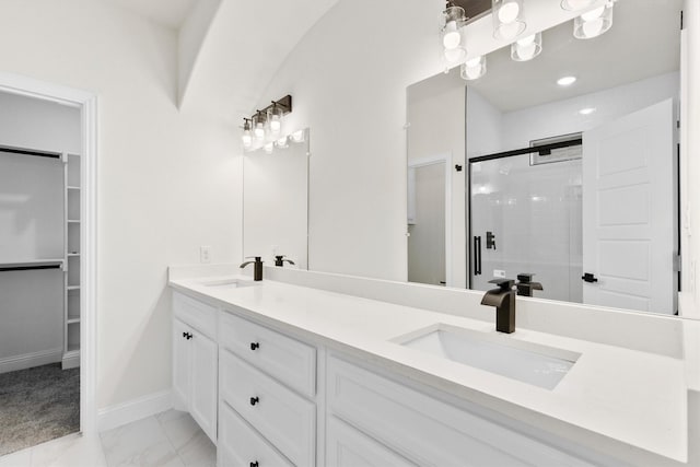bathroom with marble finish floor, a shower stall, a spacious closet, and a sink