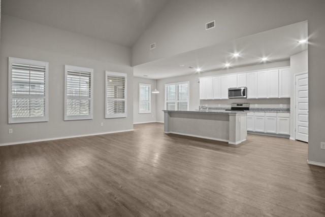 kitchen featuring dark wood finished floors, stainless steel appliances, visible vents, open floor plan, and white cabinets