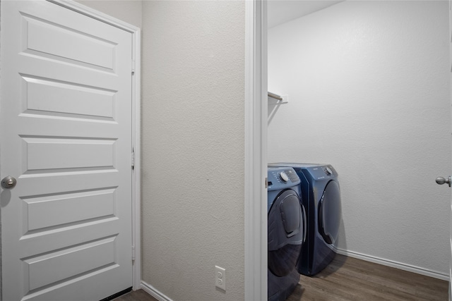 clothes washing area with dark wood finished floors, a textured wall, separate washer and dryer, laundry area, and baseboards