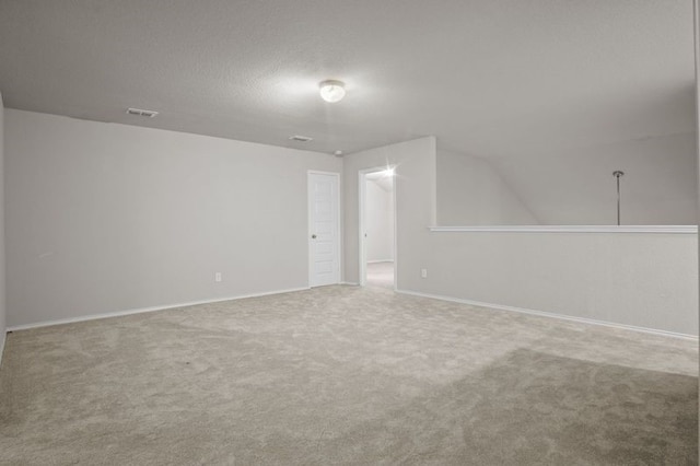 unfurnished room with a textured ceiling, carpet floors, visible vents, and baseboards