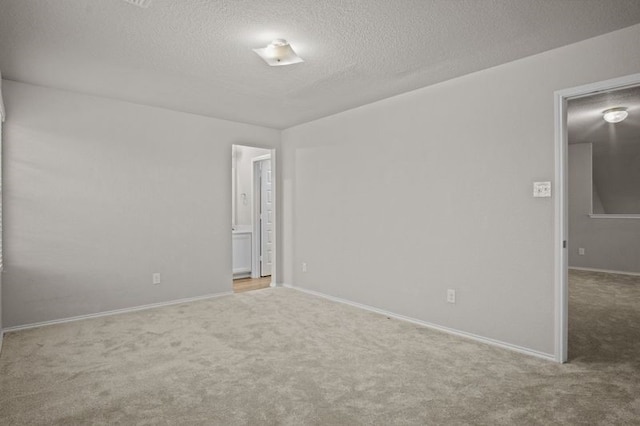 carpeted spare room with a textured ceiling and baseboards