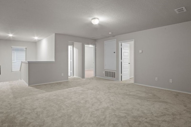 spare room with a textured ceiling, carpet floors, and visible vents