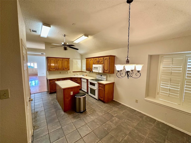 kitchen with a center island, lofted ceiling, light countertops, visible vents, and white appliances