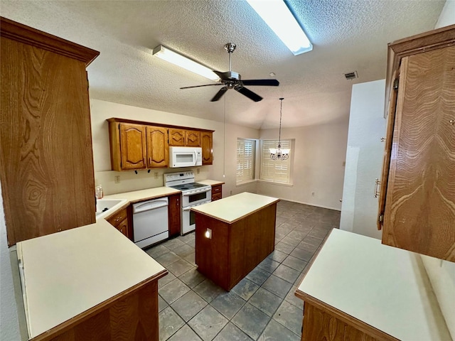 kitchen with light countertops, visible vents, brown cabinetry, a kitchen island, and white appliances