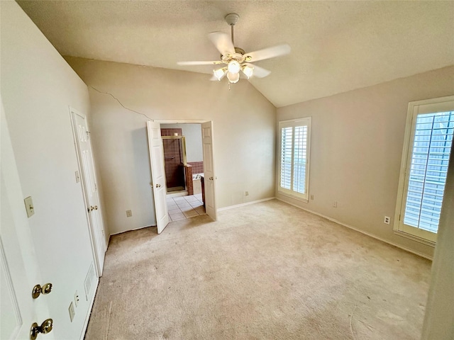 unfurnished bedroom featuring light colored carpet, multiple windows, and vaulted ceiling