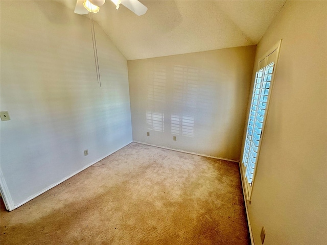 carpeted spare room with vaulted ceiling and a ceiling fan