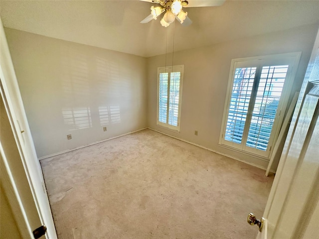 carpeted empty room with baseboards and a ceiling fan