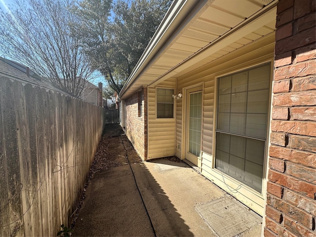 view of side of property featuring brick siding and fence