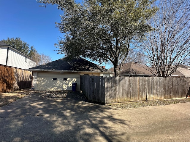 exterior space featuring a garage, fence, driveway, and an outdoor structure