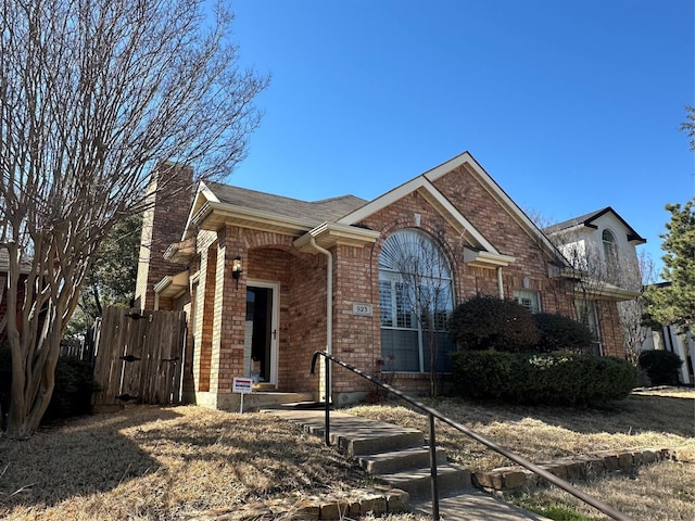 view of front facade featuring brick siding and a gate