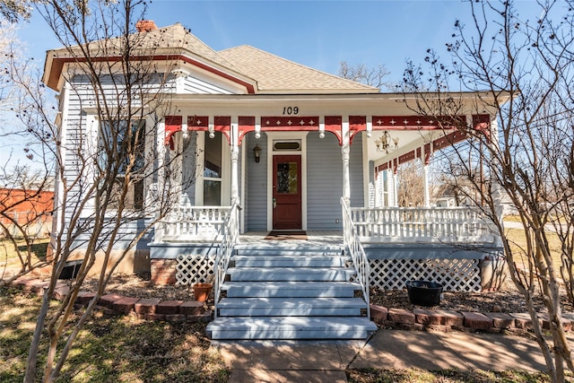 victorian-style house featuring a shingled roof and a porch