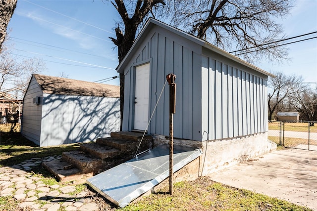 view of outbuilding featuring entry steps, a gate, fence, and an outbuilding