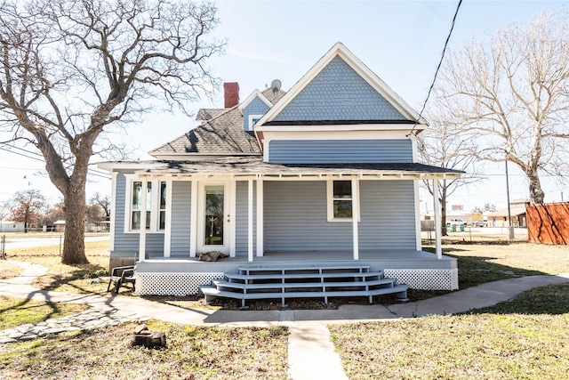 rear view of property with a porch and roof with shingles