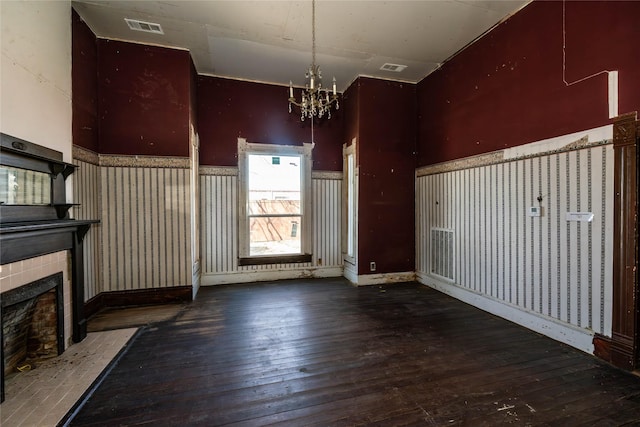 interior space with visible vents, a tiled fireplace, a notable chandelier, and hardwood / wood-style floors