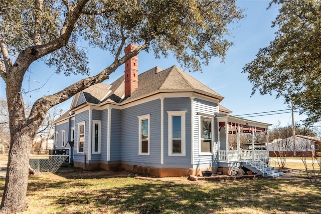 view of home's exterior featuring a yard, a chimney, a porch, a shingled roof, and fence