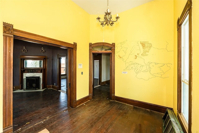 hall featuring dark wood-style flooring, a towering ceiling, baseboards, and an inviting chandelier