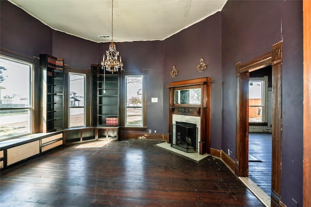 unfurnished dining area with a fireplace, visible vents, a chandelier, baseboards, and hardwood / wood-style flooring