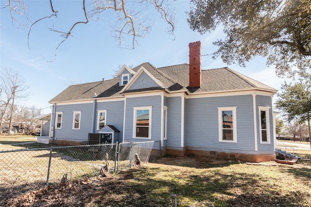 rear view of property with a shingled roof, a yard, fence, and a chimney