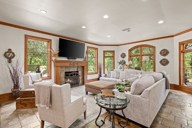 living area with a tile fireplace, baseboards, recessed lighting, crown molding, and stone tile flooring