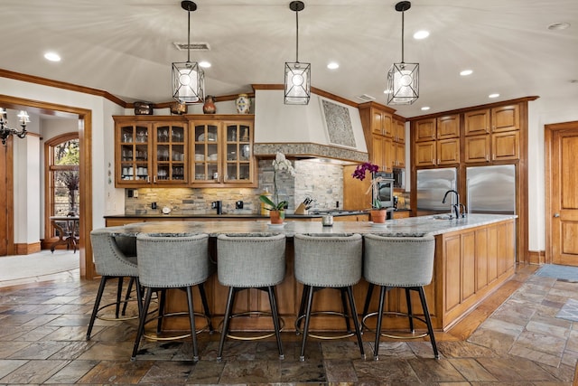 kitchen with stone tile floors, decorative backsplash, crown molding, light stone countertops, and a sink