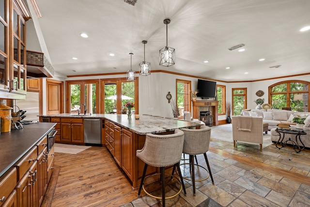 kitchen with stainless steel dishwasher, brown cabinets, ornamental molding, recessed lighting, and a kitchen bar