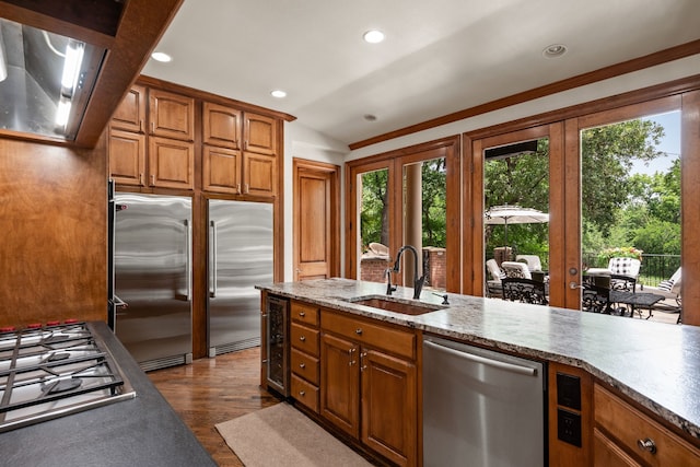kitchen with a sink, appliances with stainless steel finishes, french doors, brown cabinets, and recessed lighting