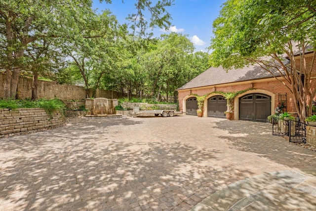 view of patio with decorative driveway, fence, and an attached garage