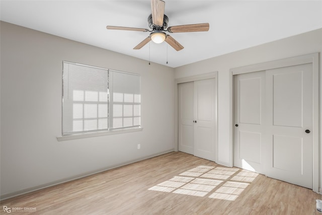 unfurnished bedroom featuring light wood-type flooring, ceiling fan, and multiple closets