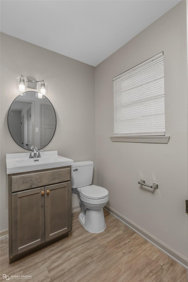 bathroom with baseboards, vanity, toilet, and wood finished floors