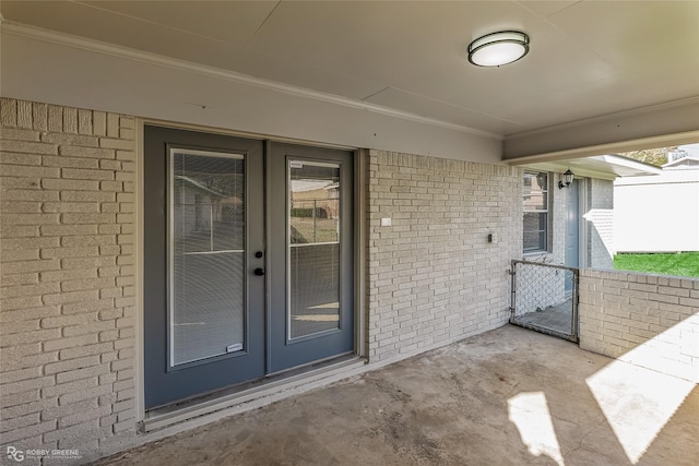 entrance to property featuring brick siding, a gate, and french doors