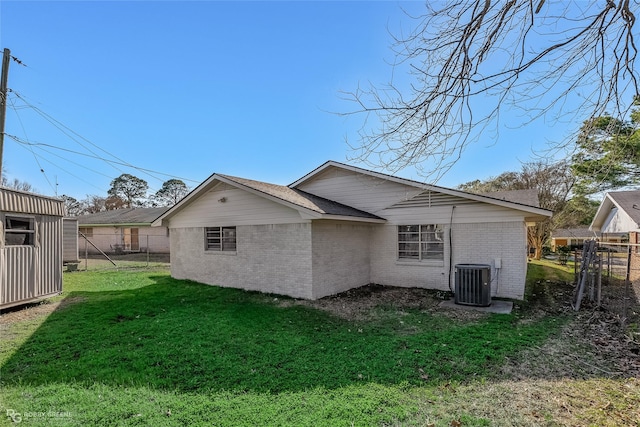 back of property featuring fence, a lawn, central AC, and brick siding