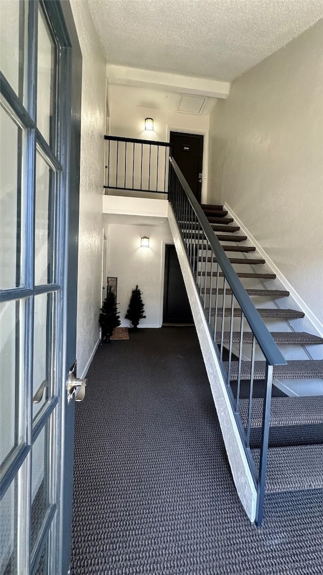 staircase with baseboards, a textured ceiling, and a textured wall