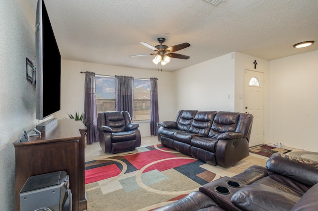 living room featuring light tile patterned flooring, ceiling fan, and a textured ceiling