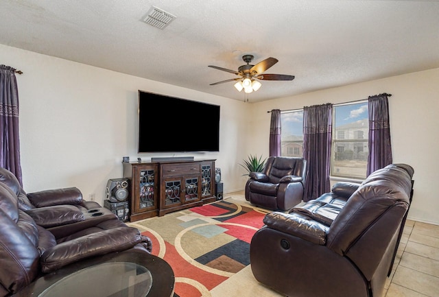 living room with light tile patterned floors, a textured ceiling, visible vents, and a ceiling fan