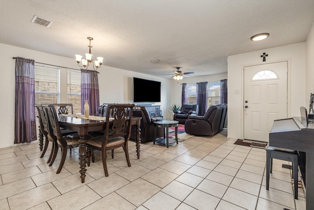 dining room featuring light tile patterned floors, visible vents, a textured ceiling, and ceiling fan with notable chandelier