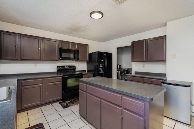 kitchen featuring black appliances, dark countertops, washing machine and dryer, and light tile patterned flooring