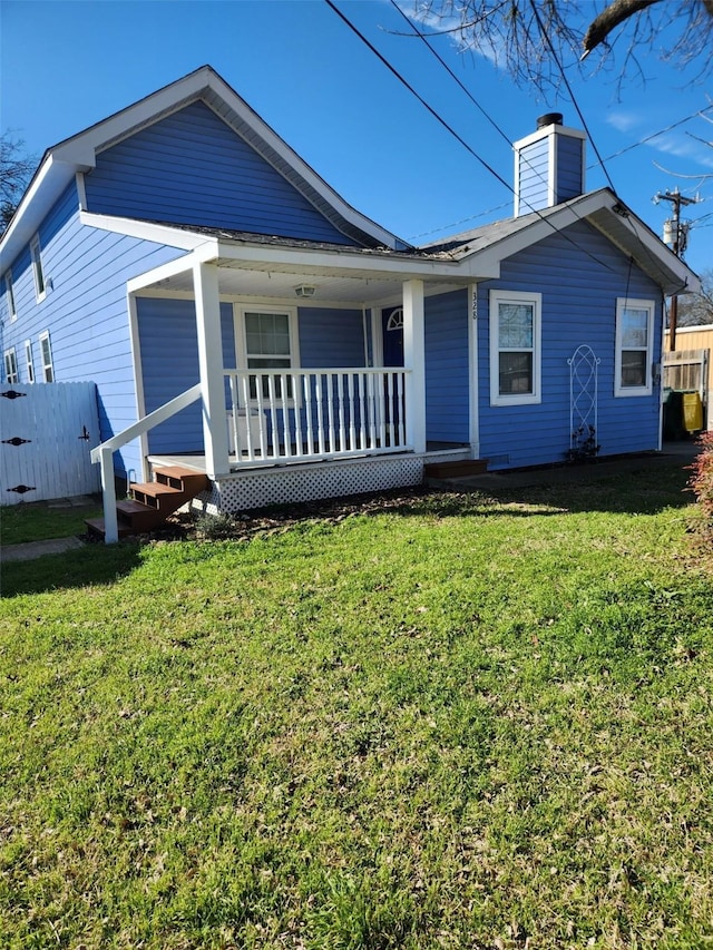 view of front of home featuring a chimney, fence, a porch, and a front yard