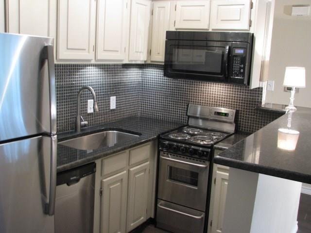 kitchen with stainless steel appliances, tasteful backsplash, a sink, and white cabinets