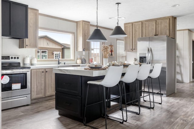 kitchen with light wood-style flooring, stainless steel appliances, a kitchen island, a kitchen breakfast bar, and light countertops