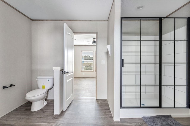 bathroom featuring toilet, a shower stall, and wood finished floors