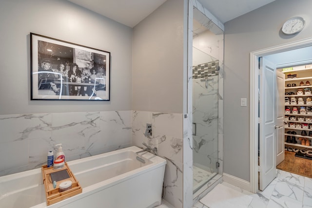 612 Skyline Bluff Dr, Fort Worth, TX 76102 - bathroom featuring marble finish flooring, a marble finish shower, a bath, a spacious closet, and tile walls