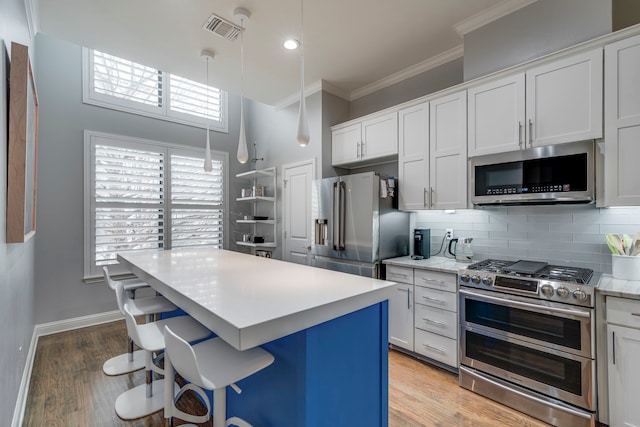 612 Skyline Bluff Dr, Fort Worth, TX 76102 - kitchen with appliances with stainless steel finishes, crown molding, light countertops, decorative backsplash, and a breakfast bar